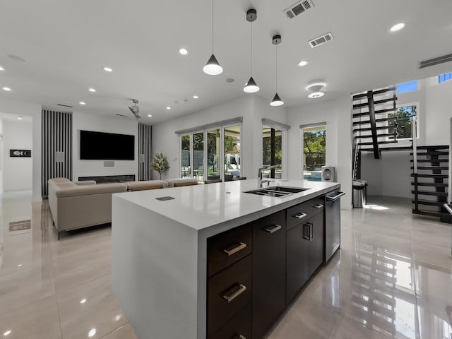 kitchen with decorative light fixtures, a spacious island, dark brown cabinets, sink, and light tile patterned floors