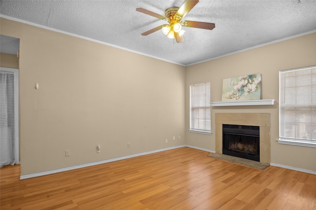 unfurnished living room with light hardwood / wood-style floors, ornamental molding, ceiling fan, and a textured ceiling