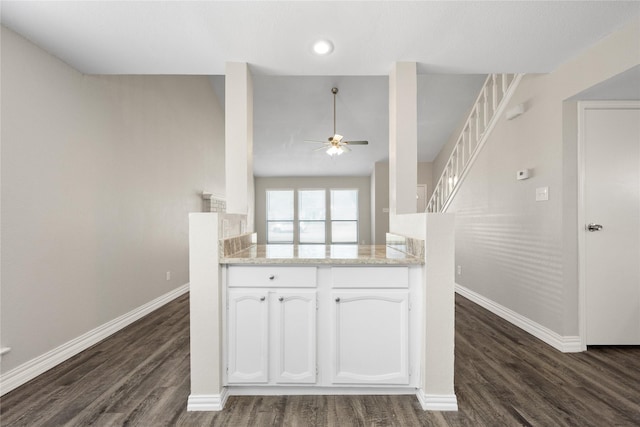 kitchen featuring kitchen peninsula, ceiling fan, dark hardwood / wood-style floors, light stone countertops, and white cabinetry