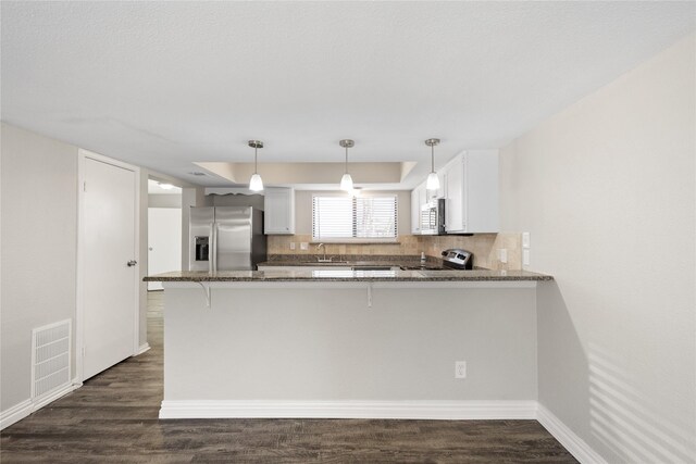 kitchen with kitchen peninsula, appliances with stainless steel finishes, and white cabinetry