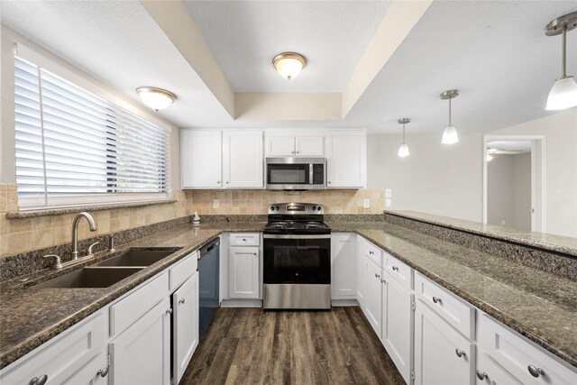 kitchen with hanging light fixtures, sink, white cabinets, and stainless steel appliances