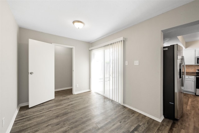 unfurnished bedroom featuring stainless steel fridge and dark wood-type flooring