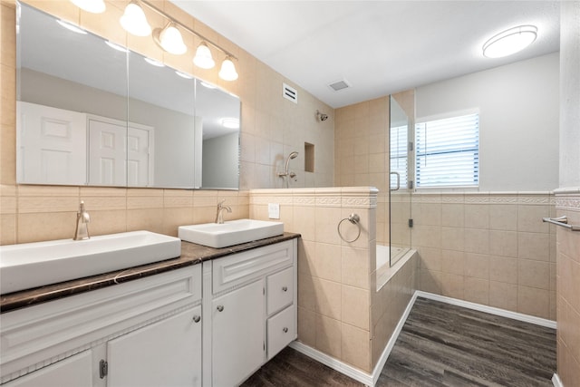 bathroom with tiled shower, vanity, tile walls, and hardwood / wood-style flooring