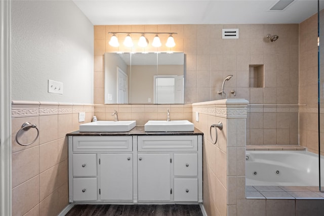 bathroom featuring hardwood / wood-style floors, vanity, tile walls, and tiled shower / bath combo