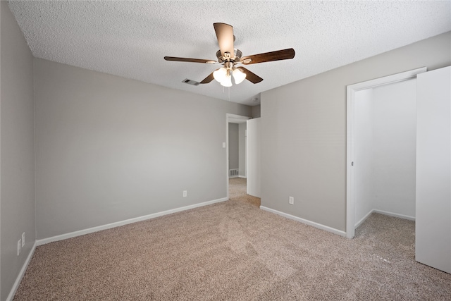 unfurnished bedroom featuring ceiling fan, a closet, light colored carpet, and a textured ceiling