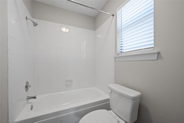 bathroom featuring bathing tub / shower combination, a textured ceiling, and toilet