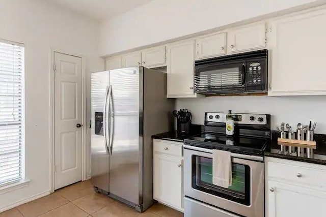 kitchen featuring white cabinets, light tile patterned floors, a healthy amount of sunlight, and stainless steel appliances