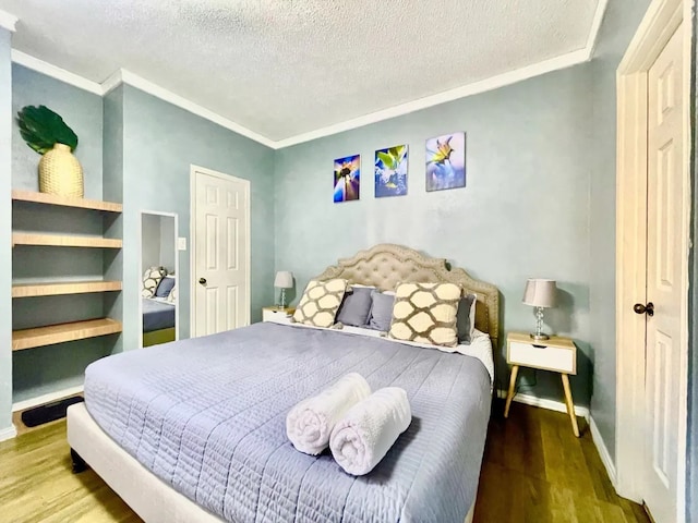 bedroom featuring hardwood / wood-style flooring, crown molding, and a textured ceiling