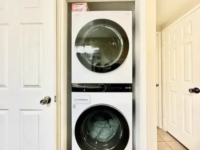 laundry room with light tile patterned flooring and stacked washer and clothes dryer