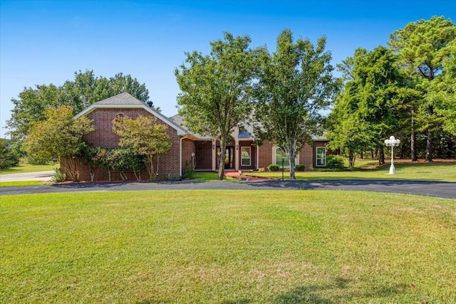 view of front of property with brick siding, driveway, and a front lawn