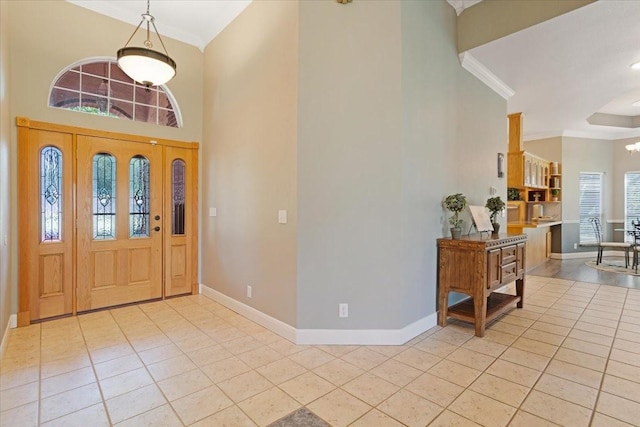 entryway with light tile patterned floors, crown molding, and a notable chandelier