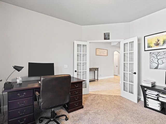 home office with light tile patterned floors, arched walkways, light colored carpet, a textured ceiling, and french doors