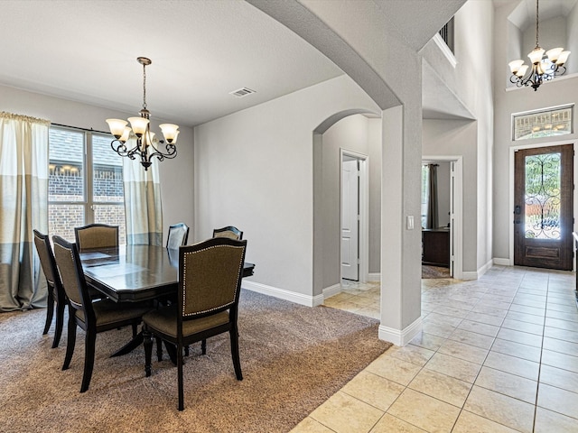 dining area featuring light colored carpet, arched walkways, light tile patterned floors, and an inviting chandelier