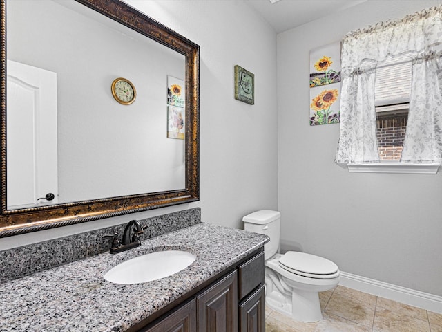 half bath with tile patterned floors, vanity, toilet, and baseboards