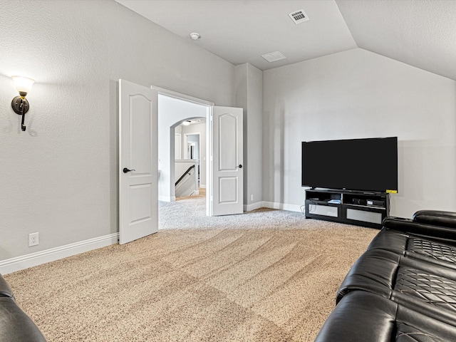 living area with arched walkways, lofted ceiling, carpet flooring, visible vents, and baseboards