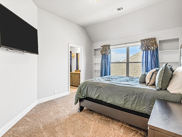 bedroom featuring ensuite bathroom, light carpet, visible vents, baseboards, and vaulted ceiling