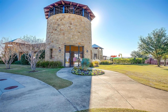 view of front of house featuring stone siding, a front yard, fence, and a gate