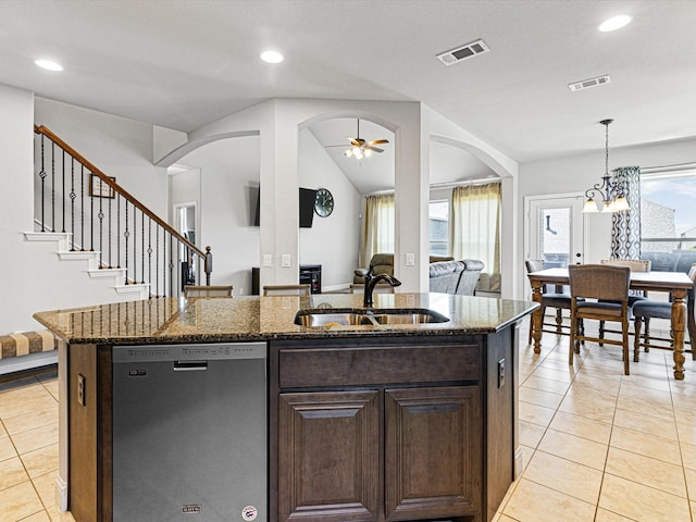 kitchen featuring visible vents, arched walkways, open floor plan, stainless steel dishwasher, and a sink