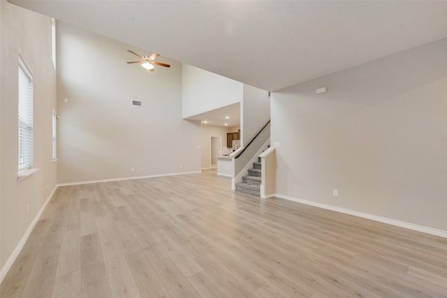 interior space with ceiling fan, light hardwood / wood-style floors, and a high ceiling