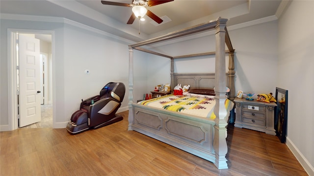 bedroom with ceiling fan, a raised ceiling, hardwood / wood-style flooring, and crown molding