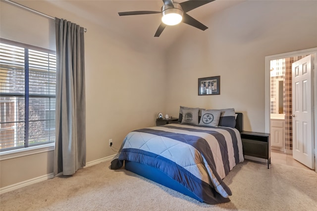 bedroom with ensuite bath, vaulted ceiling, light colored carpet, and ceiling fan