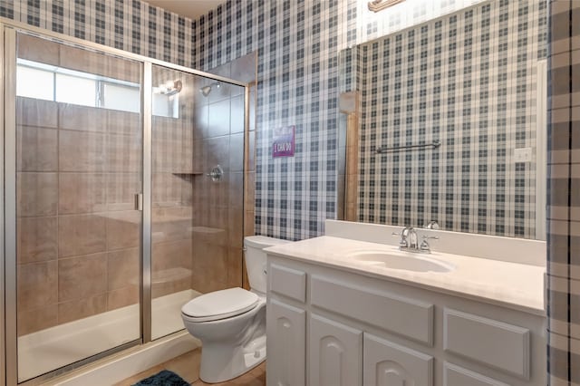 full bathroom featuring vanity, a shower stall, toilet, and wallpapered walls