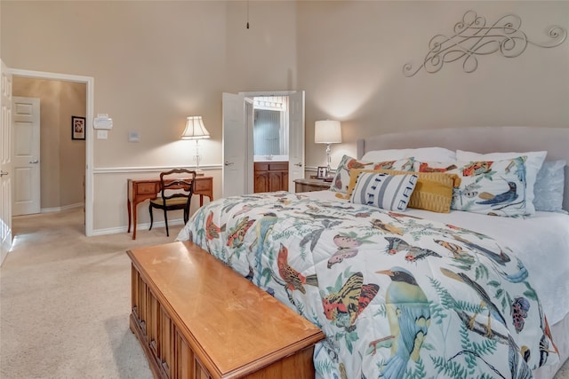 bedroom with light carpet, a high ceiling, connected bathroom, and baseboards