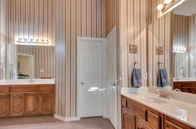 full bathroom with tile patterned floors, two vanities, a sink, and wallpapered walls