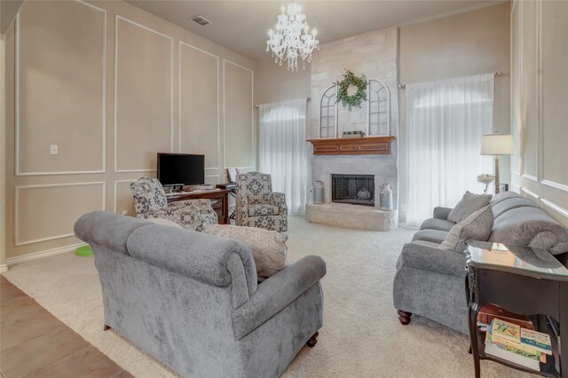 carpeted living room featuring a large fireplace and a notable chandelier