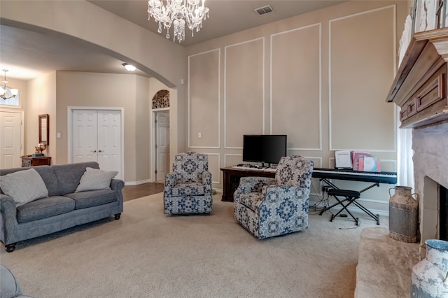 living room with carpet flooring, an inviting chandelier, and a high end fireplace