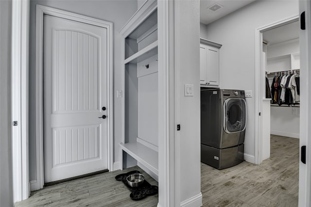 washroom featuring washer / clothes dryer, light hardwood / wood-style flooring, and cabinets