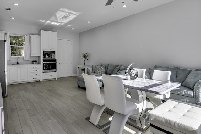 dining space with sink, ceiling fan, and light wood-type flooring