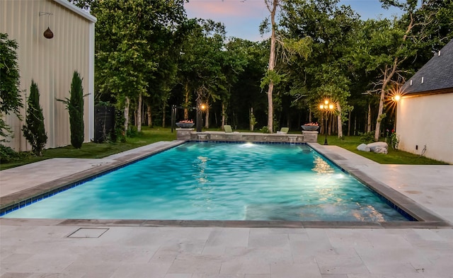 pool at dusk featuring pool water feature