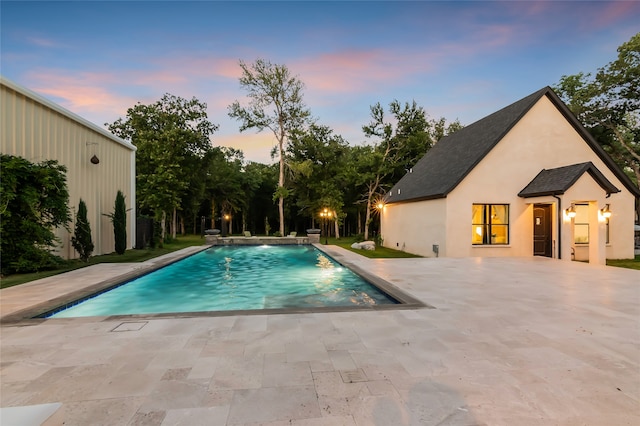 pool at dusk with a patio area