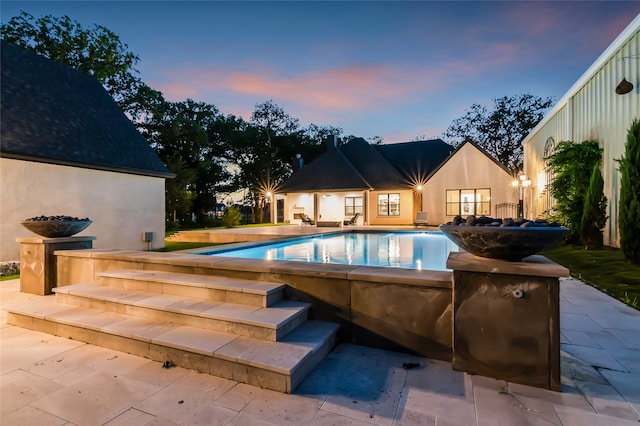 pool at dusk featuring a patio