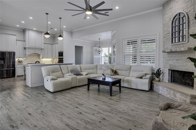 living room with light wood-type flooring, crown molding, and ceiling fan with notable chandelier