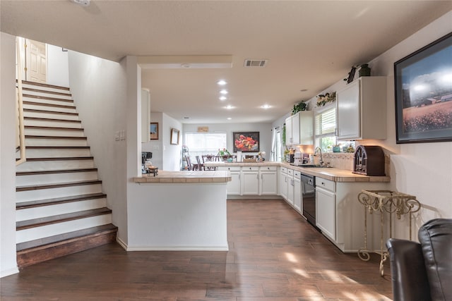 kitchen with dark hardwood / wood-style flooring, white cabinets, dishwasher, sink, and kitchen peninsula