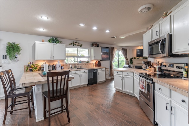 kitchen featuring appliances with stainless steel finishes, sink, wood-type flooring, and tile countertops