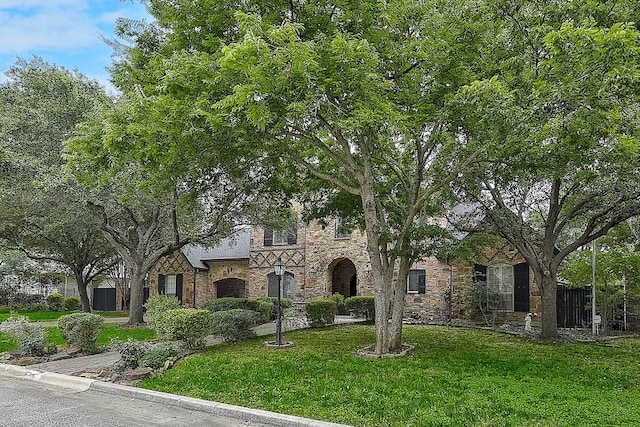 tudor house with stone siding and a front yard