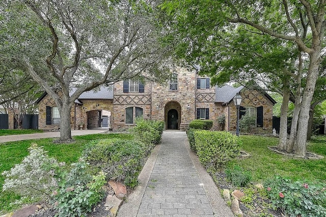 tudor house featuring driveway, a front lawn, and brick siding