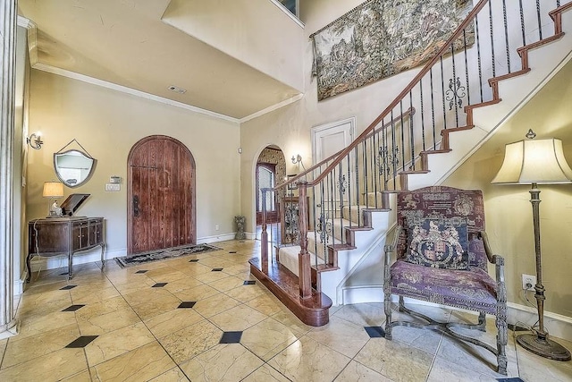 entryway featuring arched walkways, crown molding, visible vents, stairway, and baseboards