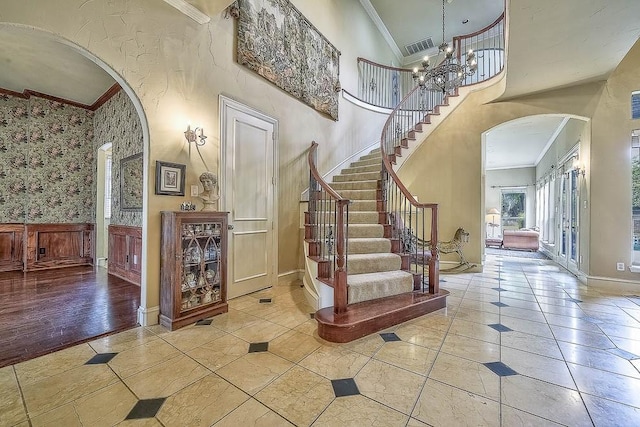 foyer entrance featuring arched walkways, a chandelier, and crown molding