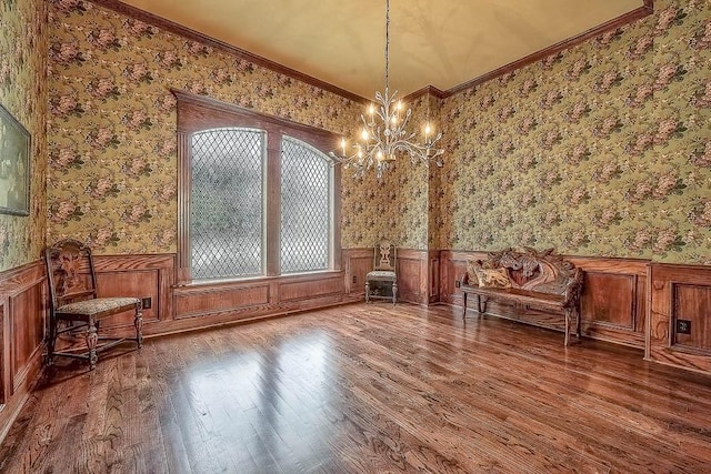 unfurnished room featuring ornamental molding, wainscoting, wood finished floors, and wallpapered walls