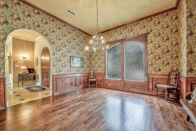 unfurnished dining area with wallpapered walls, visible vents, wood finished floors, and wainscoting