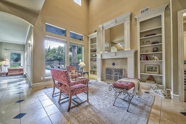 living area with tile patterned flooring, a fireplace, built in features, and arched walkways