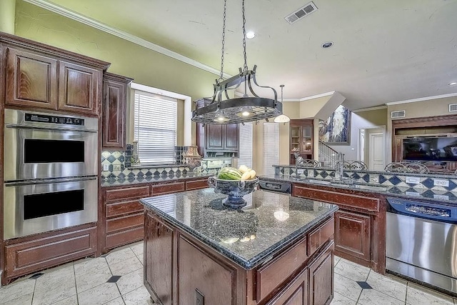 kitchen with a center island, hanging light fixtures, appliances with stainless steel finishes, ornamental molding, and dark stone counters