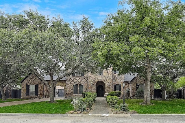 tudor house with fence, concrete driveway, and a front yard