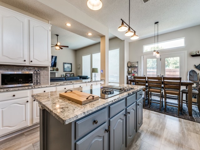 kitchen with white cabinetry, gray cabinets, a kitchen island, and hanging light fixtures