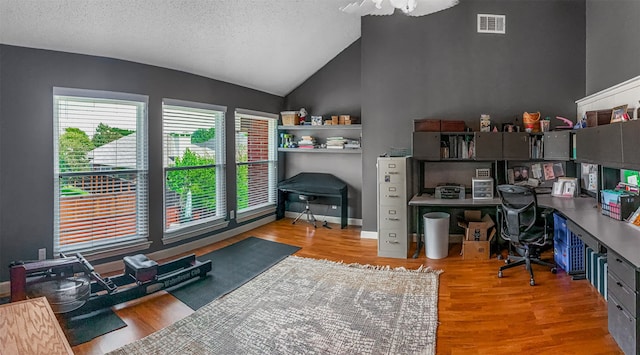 home office featuring light wood-type flooring, vaulted ceiling, and a textured ceiling