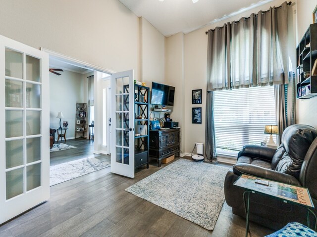 living room featuring french doors, a towering ceiling, and wood-type flooring